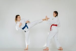 Dynamic shot of two women practicing martial arts techniques in a studio setting.